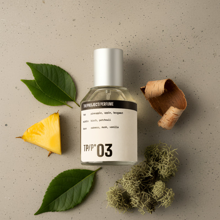 Perfume bottle labeled 'TPP 03' with a pineapple, leaves, and moss on a textured beige background