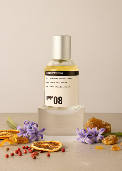 Perfume bottle labeled 'TPP 08' with dried flowers and fruits on a neutral background